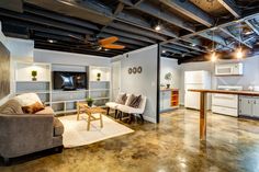 a living room filled with furniture and a flat screen tv mounted to the wall next to a kitchen