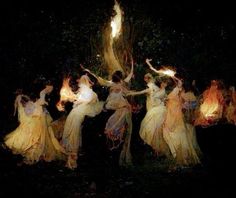 a group of women dressed in white and yellow dancing around a tree with fire torches