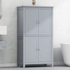 a bathroom with a sink, toilet and gray cabinet in the corner by the bathtub