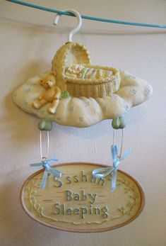 a baby sleeping sign hanging from a clothes line with a teddy bear in a crib