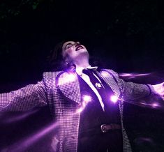 a woman with her arms outstretched in the air while wearing a purple suit and tie