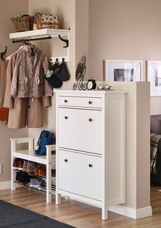 a white dresser sitting next to a closet filled with clothes