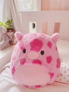 a pink stuffed animal sitting on top of a bed