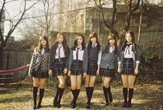 four girls in school uniforms are standing together