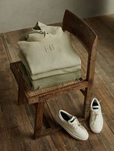 a pair of white shoes sitting on top of a wooden chair next to a bag