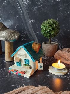 a small toy house with a lit candle on the table next to it and other decorations