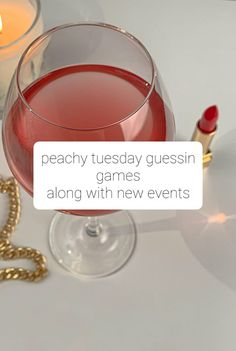 a wine glass filled with red liquid next to a gold chain and a lit candle