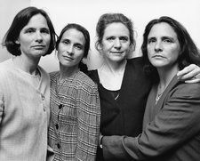 black and white photograph of three women standing next to each other in front of a wall