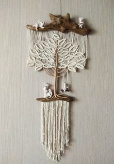 a wall hanging made out of wood and macrame with birds on it's branches