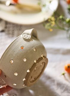 a person is holding a ceramic teapot with holes in it and the lid open