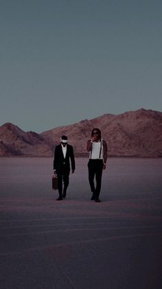 two men in tuxedos are walking through the desert