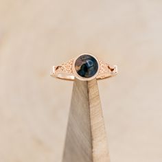 a close up of a ring with a stone in the center on a wooden stand