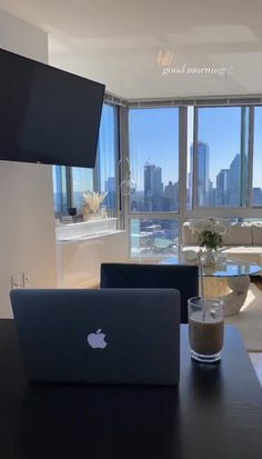 an open laptop computer sitting on top of a wooden table in front of a window