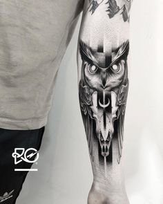 a man's arm with an owl and cross tattoo on it