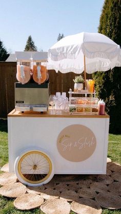 an ice cream cart is set up in the yard with umbrellas and drinks on it