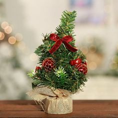 a small christmas tree sitting on top of a wooden table next to a red bow