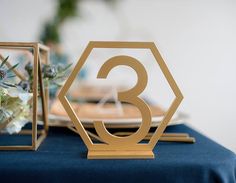 the table is set up with gold numbers and floral centerpieces, along with blue linen