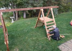 an older man working on a wooden swing set in the yard with his child's toys