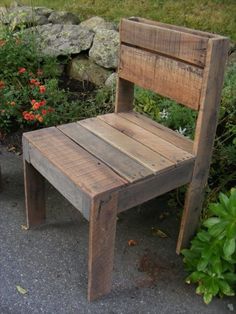 a wooden chair sitting next to some flowers