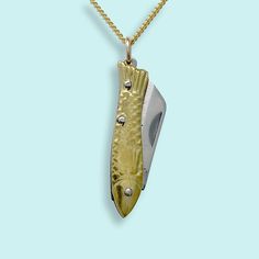 A tiny gold fish folding knife with a sharp blade on a gold curb chain. Metal: Stainless steel blade, 18kt gold-plated chain Size: 1" L knife Lobster Clasp Available in 16", 18", and 20" chain (18" Fits Most) Chain is made in the USA, Knife is made in China Word to the wise: This is a real knife and the blade is sharp. Don't wear it with the knife open. Keep it out of reach of children. Use caution when opening and closing it (if you've never opened a pocket knife, please take a minute to find a YouTube video to learn).