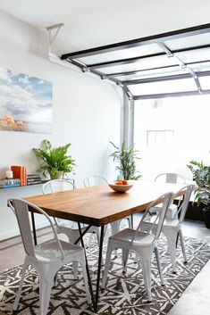 a dining room table with white chairs and a bowl of fruit on top of it