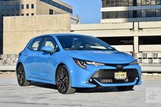 a blue car is parked in front of some large buildings and concrete slabs with no people around it