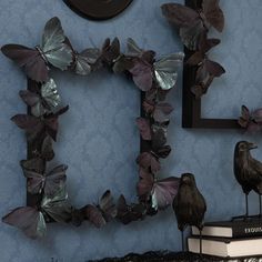 two birds sitting on top of a table next to a clock and some butterfly decorations