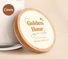 a white candle with a wooden lid next to a glass container that says golden hour