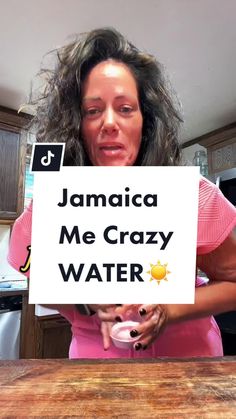 a woman holding up a sign that says jamaica me crazy water on the table in front of her