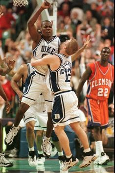 two basketball players collide as they jump for the ball in front of an audience