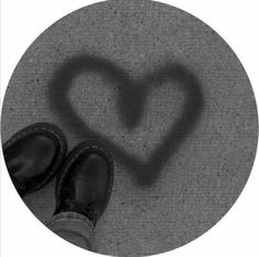 a pair of black shoes sitting on top of a floor next to a heart shaped shadow