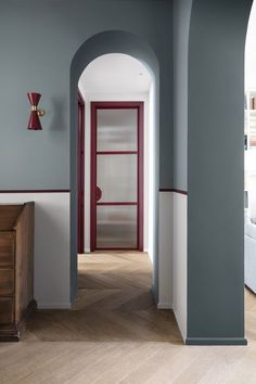 the hallway is painted in blue and white with red trim on the door, along with an arched doorway that leads to another room