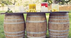 two wooden barrels with drinks on them sitting in the grass