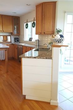 a kitchen with wooden floors and white walls, has granite counter tops on the island