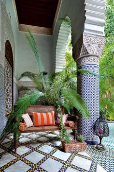 an outdoor area with blue and white tiles on the floor, potted plants, and a bench