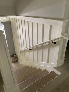 the stairs are made of wood and have white railings on each side with black handles