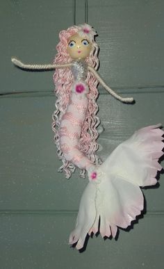 a pink and white mermaid doll hanging from a hook on a door way with stars in the background