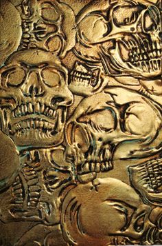 a group of skulls that are on a metal surface with some gold colored foil over it