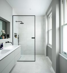 a bathroom with a walk in shower next to two sinks