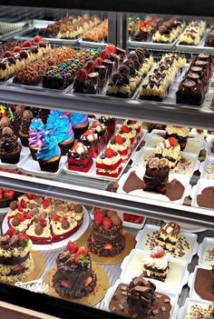 a display case filled with lots of different types of cakes and cupcakes on plates