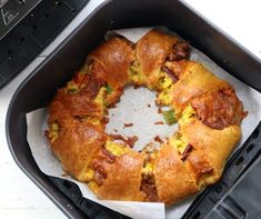 an egg and bacon croissant in a black container