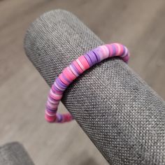 a pink and purple striped caterpillar sitting on top of a gray couch next to a chair