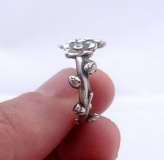 someone is holding a silver ring with flowers on it