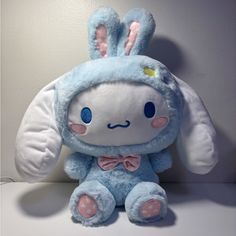 a blue stuffed rabbit sitting on top of a white table next to a gray wall