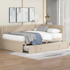 a bed with two drawers underneath it in a room next to a window and wooden floors