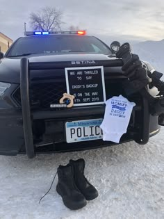 a police car parked in the snow with its license plate on it's hood