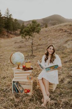 a woman is sitting on a crate in the middle of a field with an apple tree