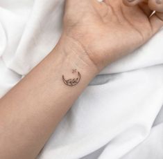 a woman's arm with a small crescent tattoo on her left wrist and the moon in the middle