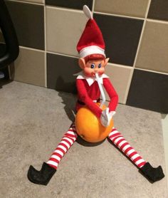 the elf is sitting on top of an orange in front of a tiled wall and floor