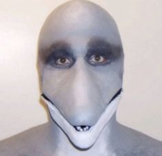 a man with white and black face paint on his face is wearing a gray mask